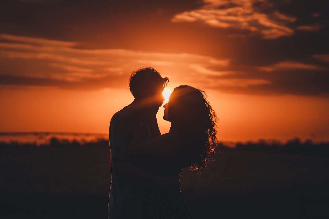 How we can help Romantic silhouette of a couple embracing at sunset, ideal for love and romance themes.